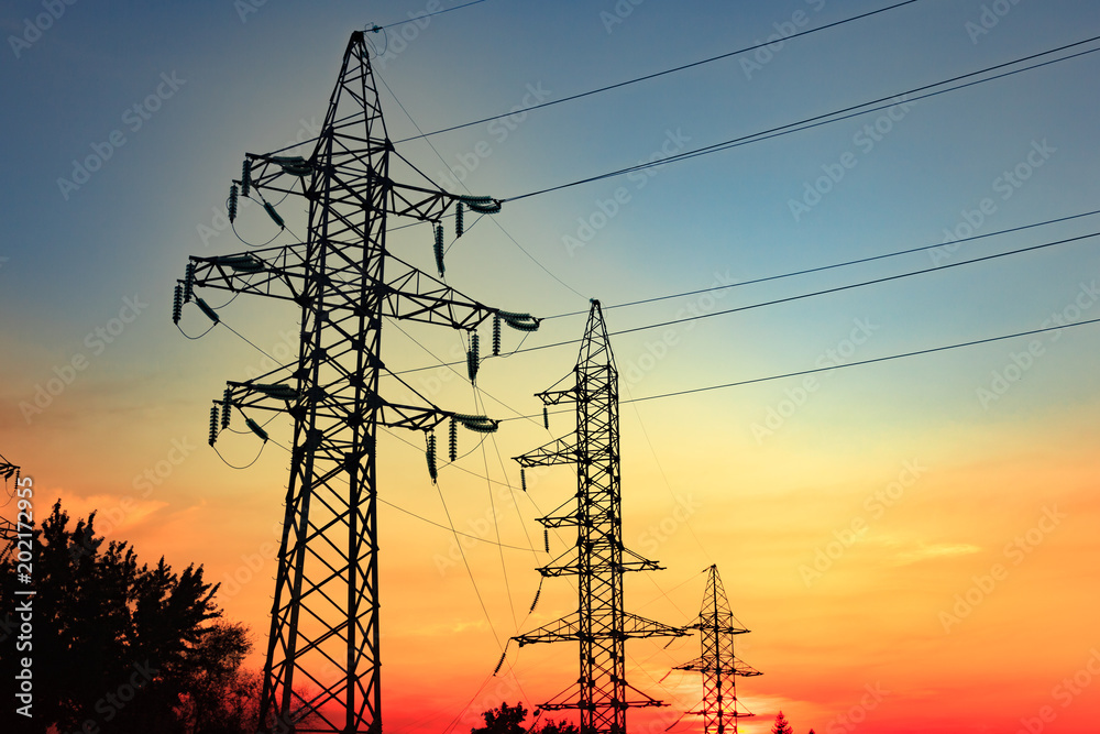 High voltage electricity pylons and transmission power lines on the blue sky and the sunset sunshine. background.