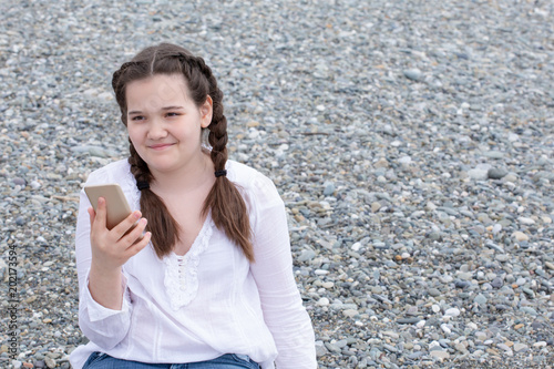 teenage girl with a phone on the beach on a sunny day
