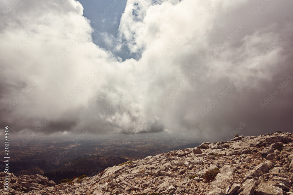 Heavy stormy clouds above high peak of Mallorca with rocks in the foreground, Spain