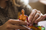 Teaching students the art of modeling. Sculpture made of plasticine. A girl molds a doll with her hands.