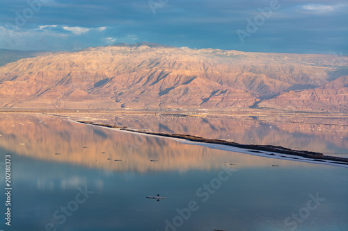 Ecology disaster in Middle East, sunset with reflection over lowest salty lake in world below sea level Dead sea, disappearance of the sea due to shallowing photo