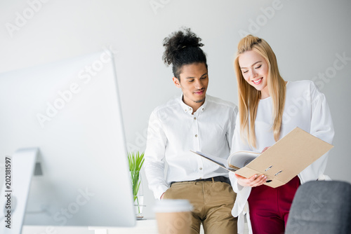 Fotografie smiling young business colleagues looking at folder with documents in office