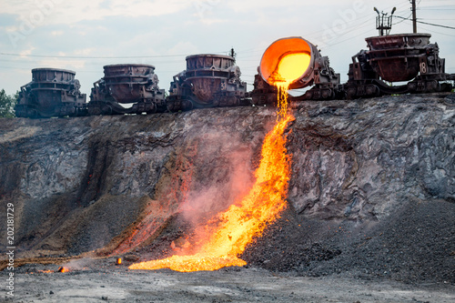 Blast furnace slag discharge at metallurgical plant, colorful hot lava flow, industrial landscape of iron foundry photo