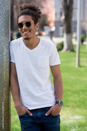 portrait of handsome young african american man in sunglasses standing with hands in pockets at sunny day
