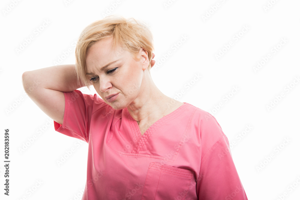 Attractive female nurse wearing pink scrubs holding back head like hurting Attractive female nurse wearing pink scrubs holding back head like hurting