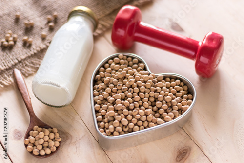 Soy milk and soybean on wooden background, alternatime source of protein for vagetarian, red dumbbell for fitness photo