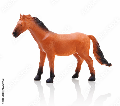 Children´s small plastic brown - black horse isolated on the white background with shadow reflection. Small childish toy in the shape of horse. Miniature of brown horse on white background with shadow