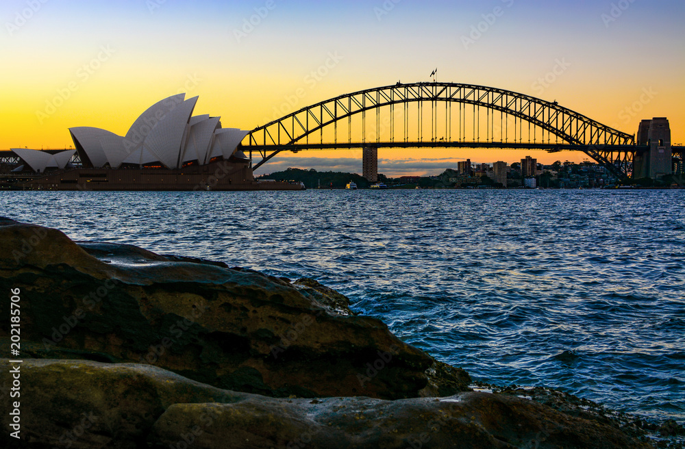 Obraz premium Iconic Sydney Harbour Bridge seen from natural shoreline at sunset