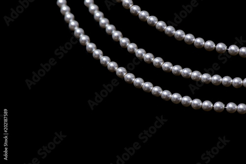 Three strings of pearls on black background.