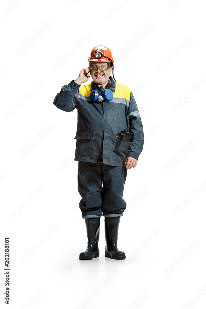 The studio shot of happy senior bearded male miner standing at the camera with smartphone on a white background.