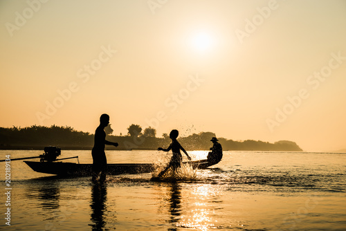 Silhouette of children playing water with friend