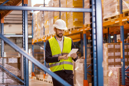 Electronic system. Smart positive man using a tablet while checking the working process in the warehouse