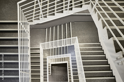 Looking down at a modern staircase with white wall as to be found in an office, hospital or an apartment.