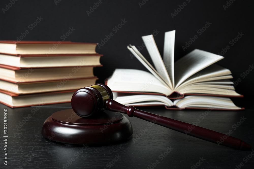 Judge gavel beside pile of books on wooden background Judge gavel beside pile of books on wooden background