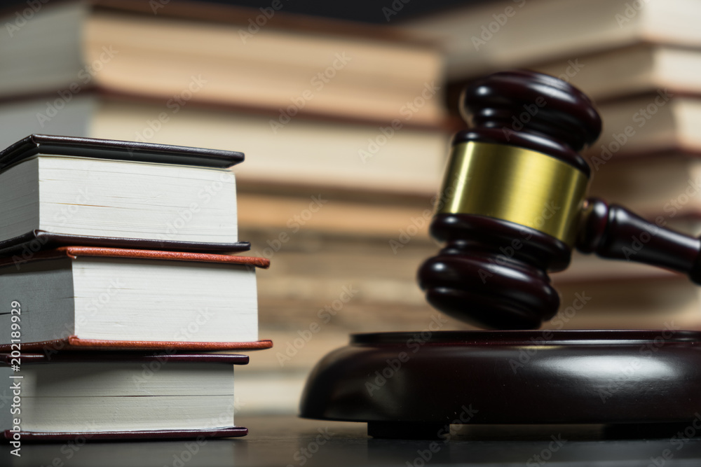 Judge gavel beside pile of books on wooden background Judge gavel beside pile of books on wooden background