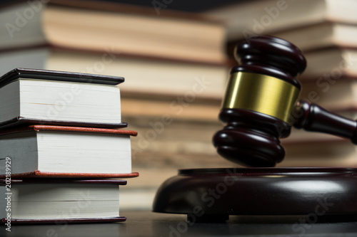 Judge gavel beside pile of books on wooden background