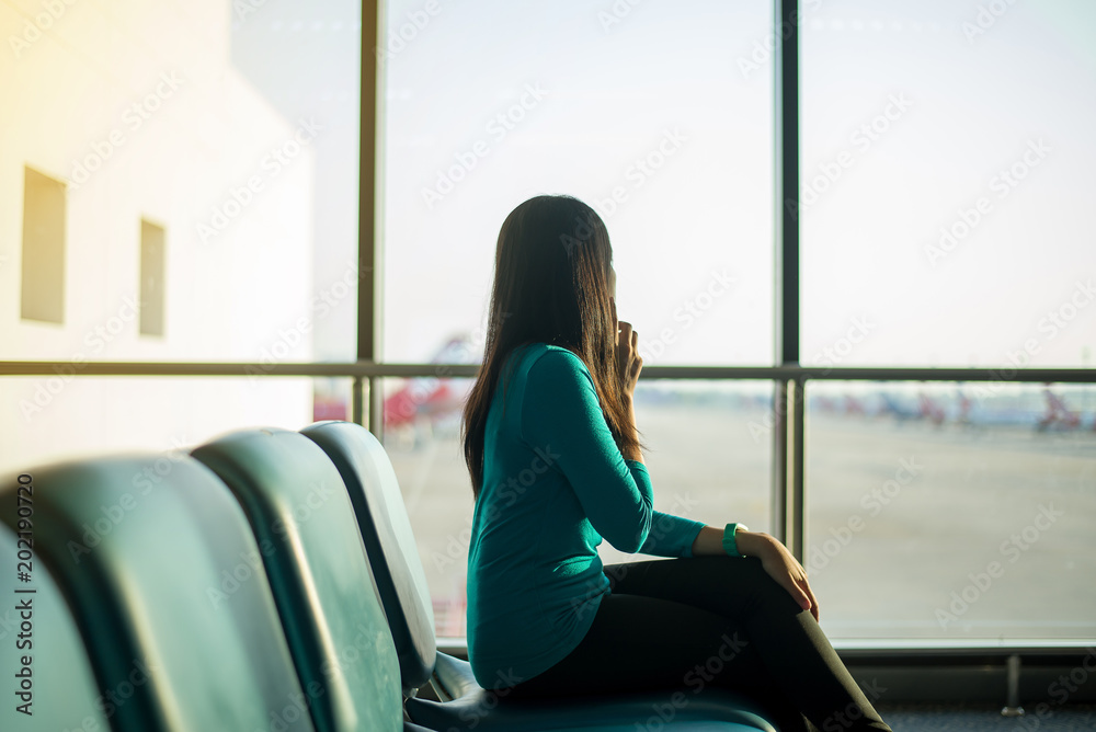 Asian woman passenger using smartphone and checking flight or online check in and travel planner at international airport