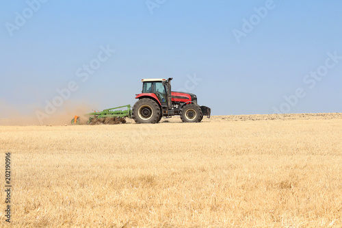 Cultivation of a wheat field on a tractor in a summer sunny day. Harvesting in agriculture