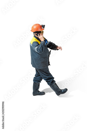The studio shot of senior bearded male miner standing at the camera on a white background.