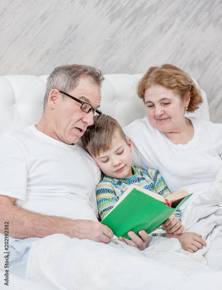grandmother and grandfather read the book to her grandson before going to bed grandmother and grandfather read the book to her grandson before going to bed