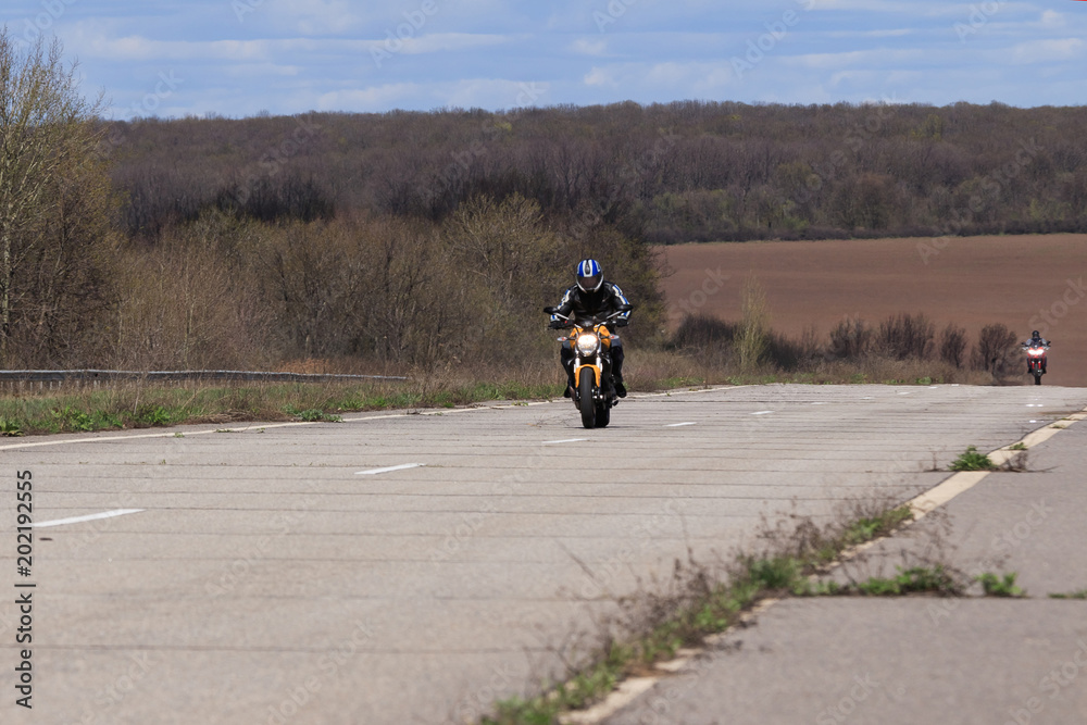 Obraz premium Male motorcyclist at the wheel of a racing motorcycle on a high-speed empty road. with pleasure passing an empty road to travel by motorcycle. Place for text, extreme sport, freedom concept