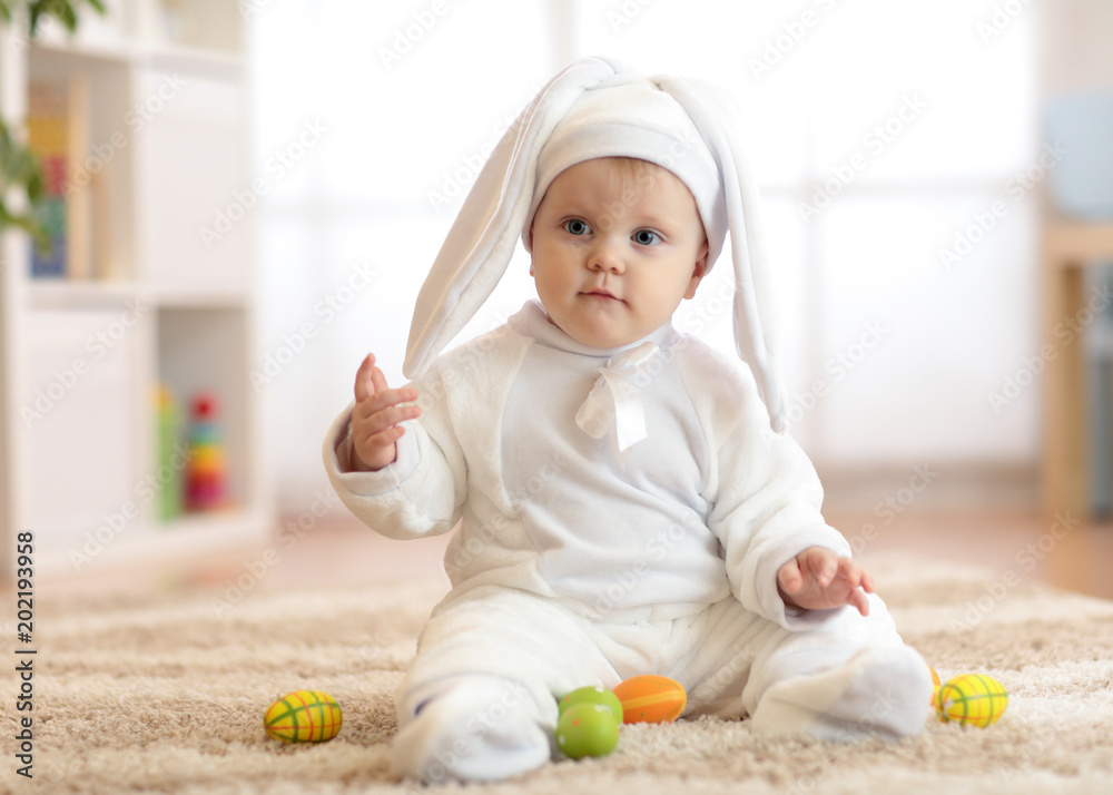 Funny cute baby child in rabbit costume sittng on froor in nursery Funny cute baby child in rabbit costume sittng on froor in nursery