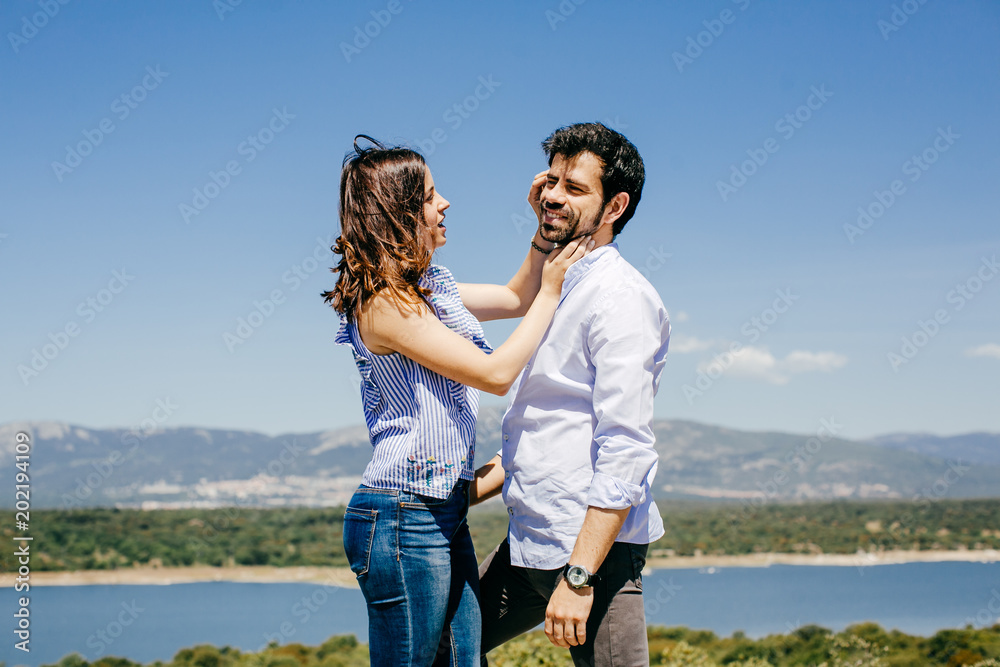 .Young happy couple in love enjoying a nice spring day in the countryside. Located on a hill overlooking a large lake. .Young happy couple in love enjoying a nice spring day in the countryside. Located on a hill overlooking a large lake.