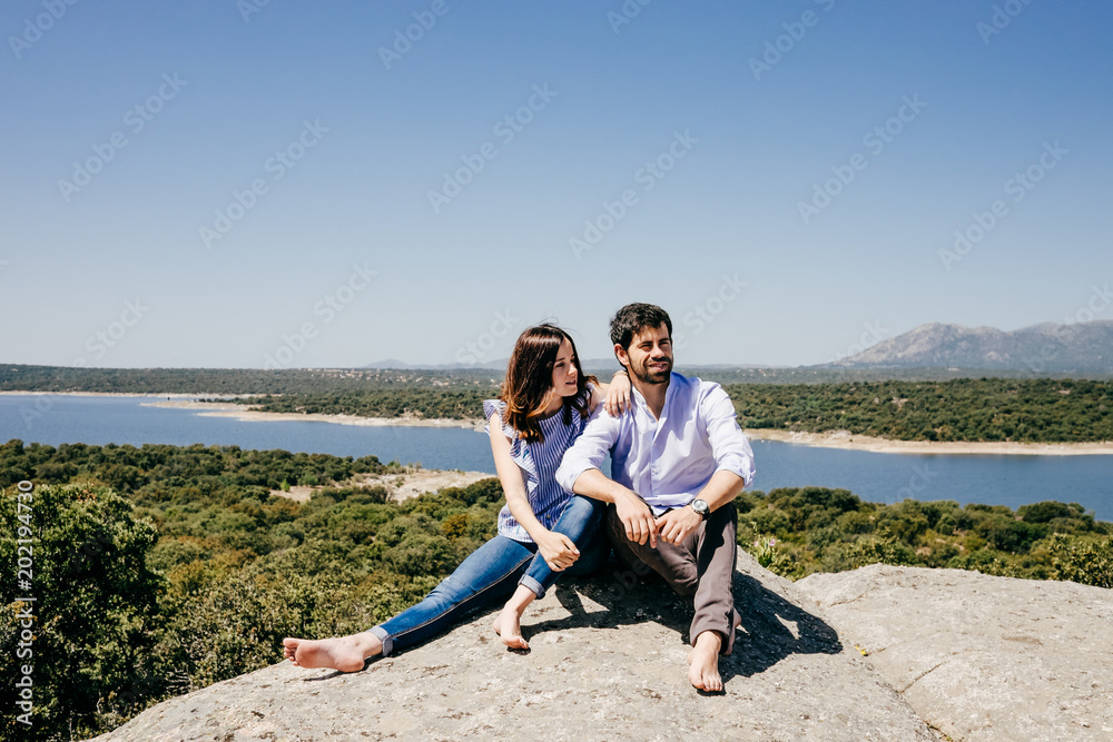 .Young happy couple in love enjoying a nice spring day in the countryside. Located on a hill overlooking a large lake.