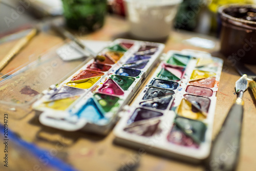 poster paints and watercolor paints on wooden table in workshop