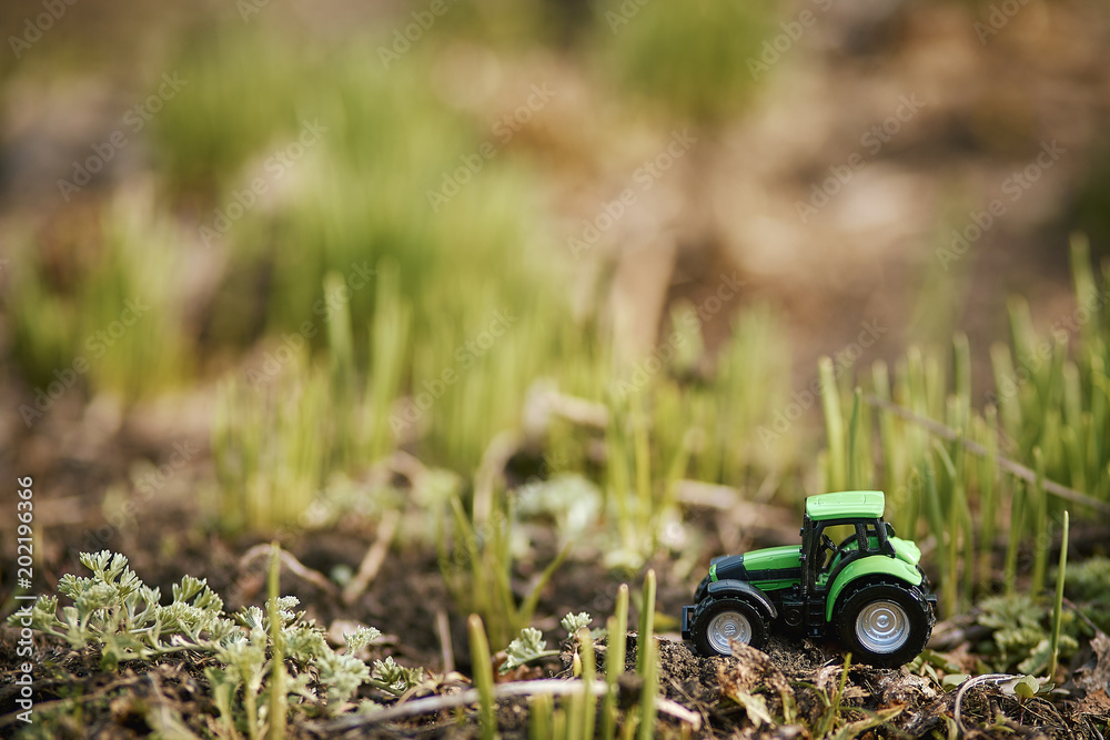 toy tractor on green grass background . Spring sowing works toy tractor on green grass background . Spring sowing works