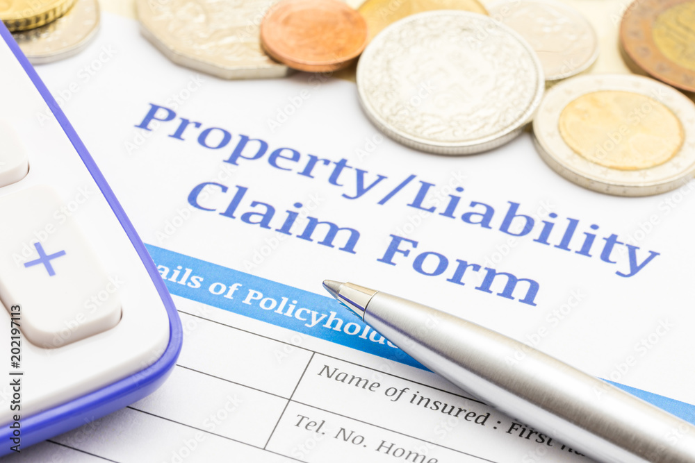 Property or Liability claim form document concept with Silver pen, Gold coins money, Plastic mini house and Calculator Property or Liability claim form document concept with Silver pen, Gold coins money, Plastic mini house and Calculator