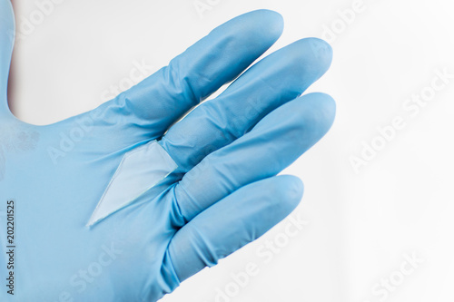 A piece of glass in the hand in the glove. Cleaning of broken glass.