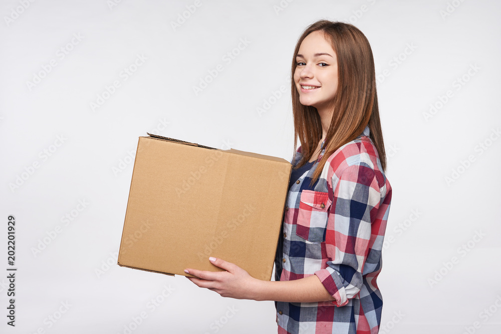 Delivery, relocation and unpacking. Smiling young woman holding cardboard box isolated Delivery, relocation and unpacking. Smiling young woman holding cardboard box isolated