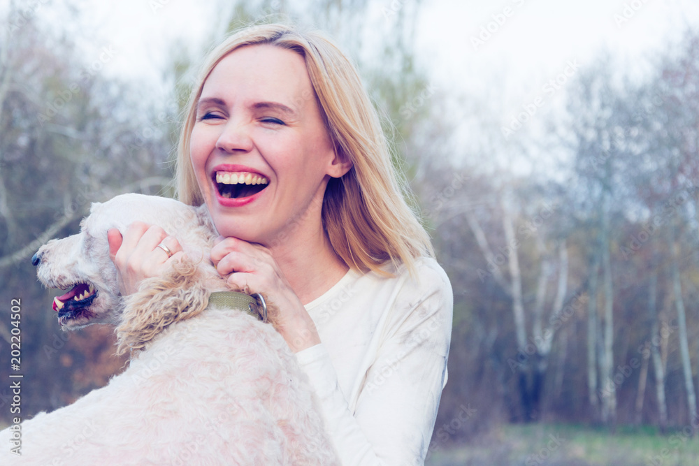 A joyful woman with a dog hugs and fools around in nature. Toned. A joyful woman with a dog hugs and fools around in nature. Toned.