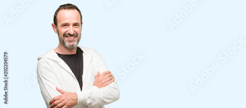 Middle age man wearing sportswear with crossed arms confident and happy with a big natural smile laughing isolated over blue background