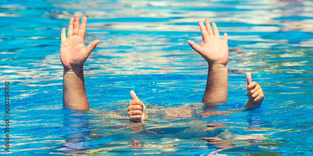  Father and son dives under the water in the pool  at summer day. Leisure and swimming at holidays.