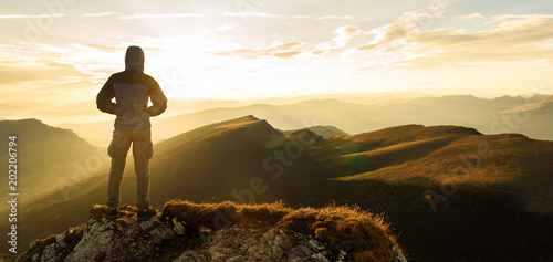 Silhouette of the man on top the peak of mountain on sunrise sky , Sport and active life onceptual design.