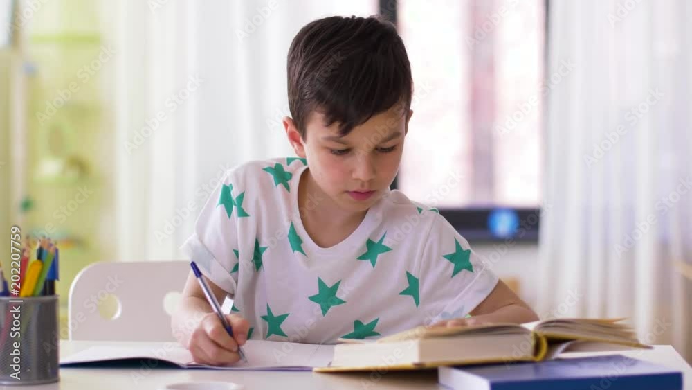 education, childhood and people concept - boy writing to notebook at home education, childhood and people concept - boy writing to notebook at home