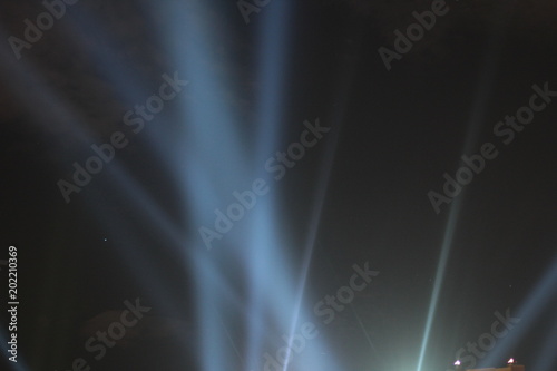 Abstract background. Searchlights shining beams of light into the black sky.