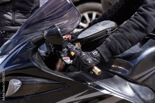 Biker hand in black gloves hold the steering wheel motorcycle close up