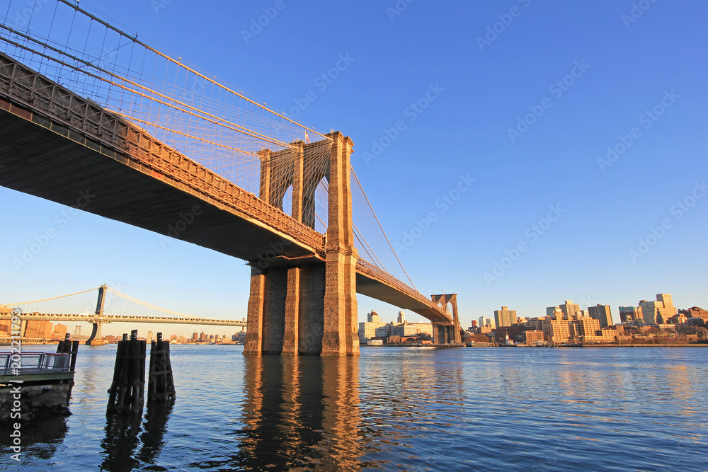 Naklejka premium Brooklyn Bridge over East River with view of New York City Lower Manhattan, waterfront at twilight, USA