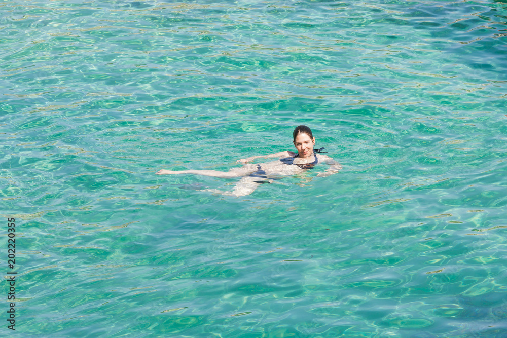 Cala Murada, Mallorca - A young woman smiling while swimming in the turquoise Mediterranean Sea at Cala Murada