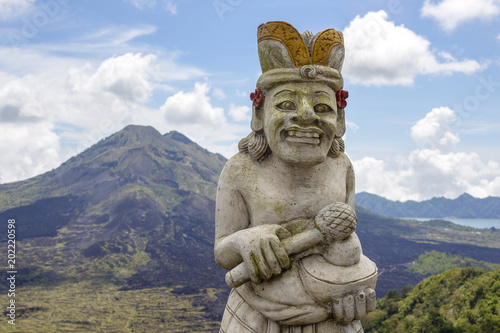 Traditional Balinese sculpture against the background of the volcano Batur. Island Bali, Indonesia © OlegD