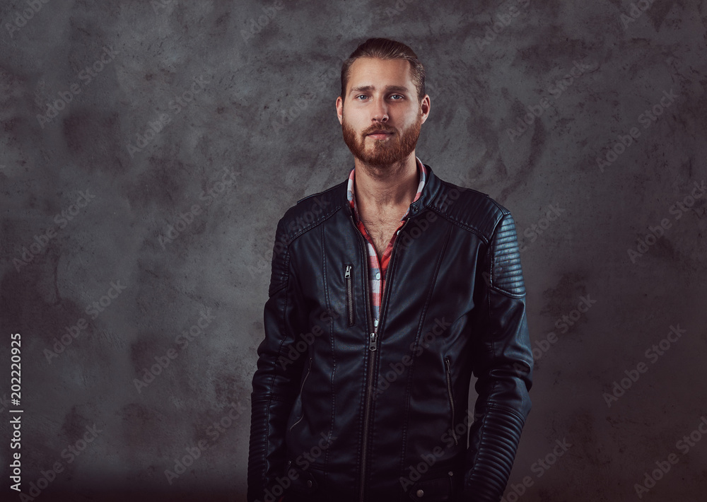 Portrait of a handsome stylish redhead man in a black leather jacket, posing in a studio. Isolated on a dark background. Portrait of a handsome stylish redhead man in a black leather jacket, posing in a studio. Isolated on a dark background.