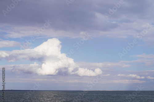 A large white cloud above the calm sea.
