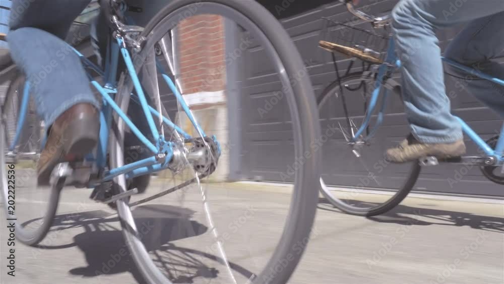 Moving shot of a young loving couple riding a their bicycles through an alley way Moving shot of a young loving couple riding a their bicycles through an alley way