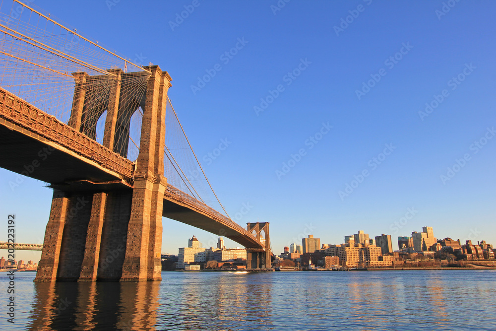 Brooklyn Bridge over East River with view of New York City Lower Manhattan, waterfront at twilight, USA