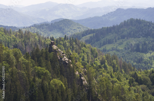 Dovbush Rocks - the famous landmark of the Carpathians, view from the neighboring mountain; Two flags on the top