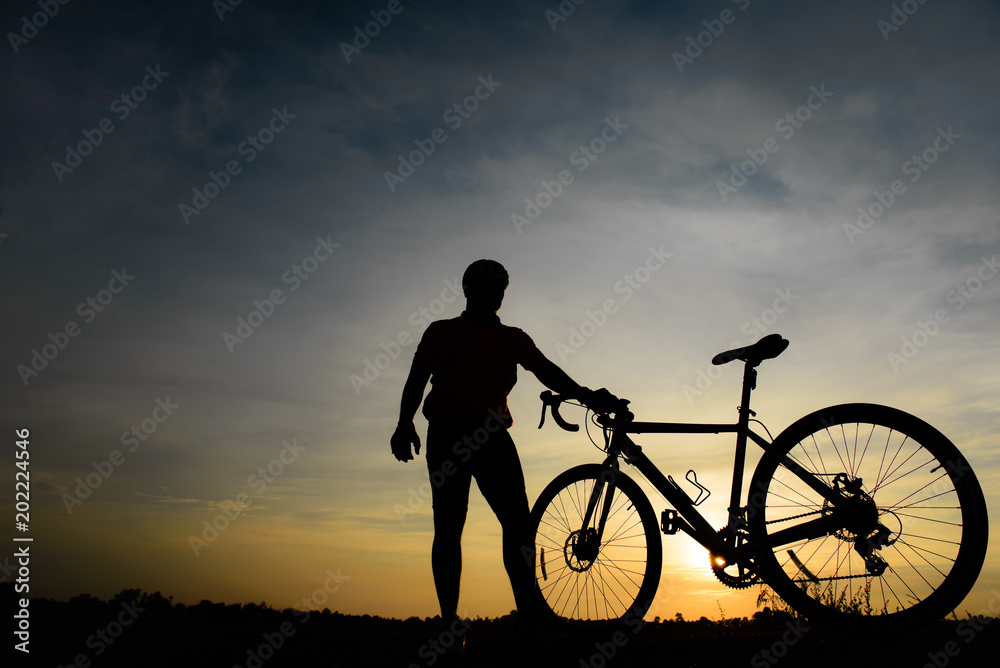 Obraz premium Silhouette of handsome man with bicycle on sunset,sport man concept