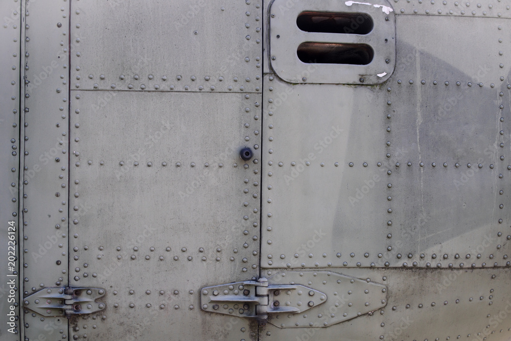 Old silver metal surface of the aircraft fuselage with rivets. Fuselage detail view. Airplane metallic fuselage detail with rivets.
